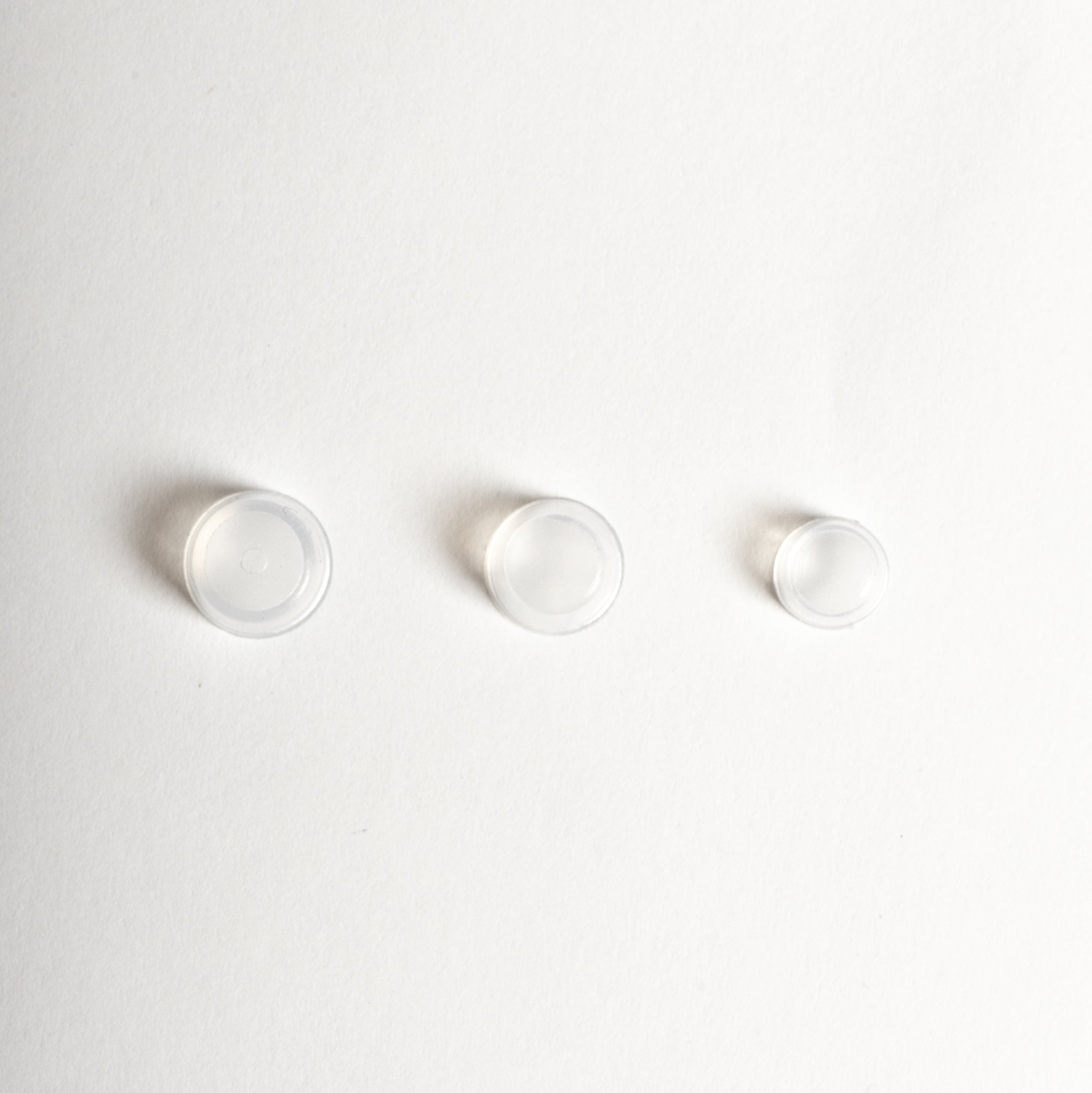 Three small white circular objects on a light gray background