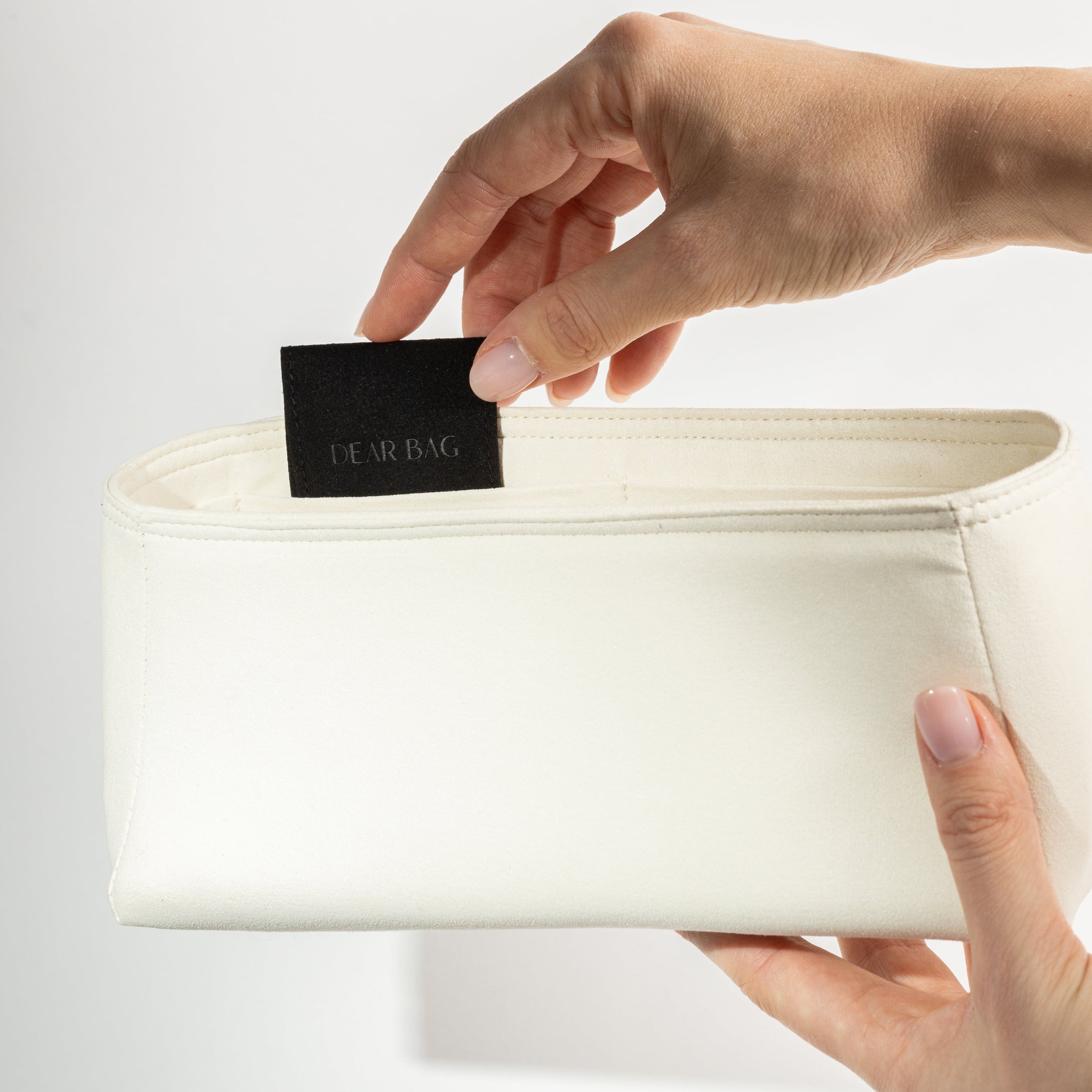 Person holding a white belt with a black label against a light gray background