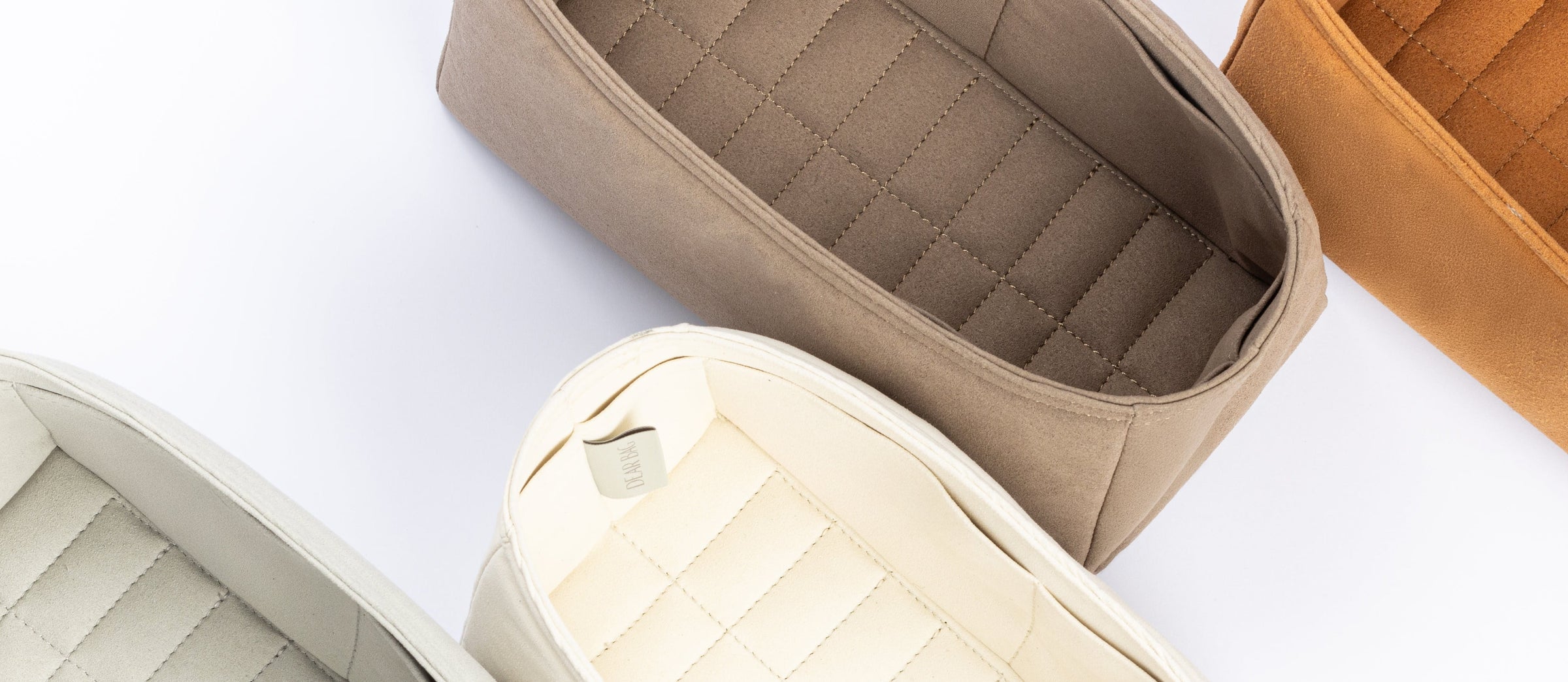 Three quilted fabric organizer pouches in beige, cream, and tan, arranged diagonally on a clean white background.